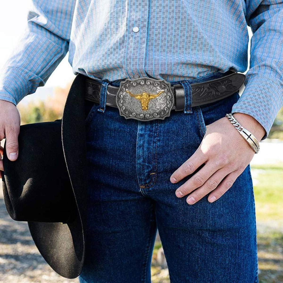 Western cowboy belt worn with jeans: black embossed strap and silver buckle with gold bull