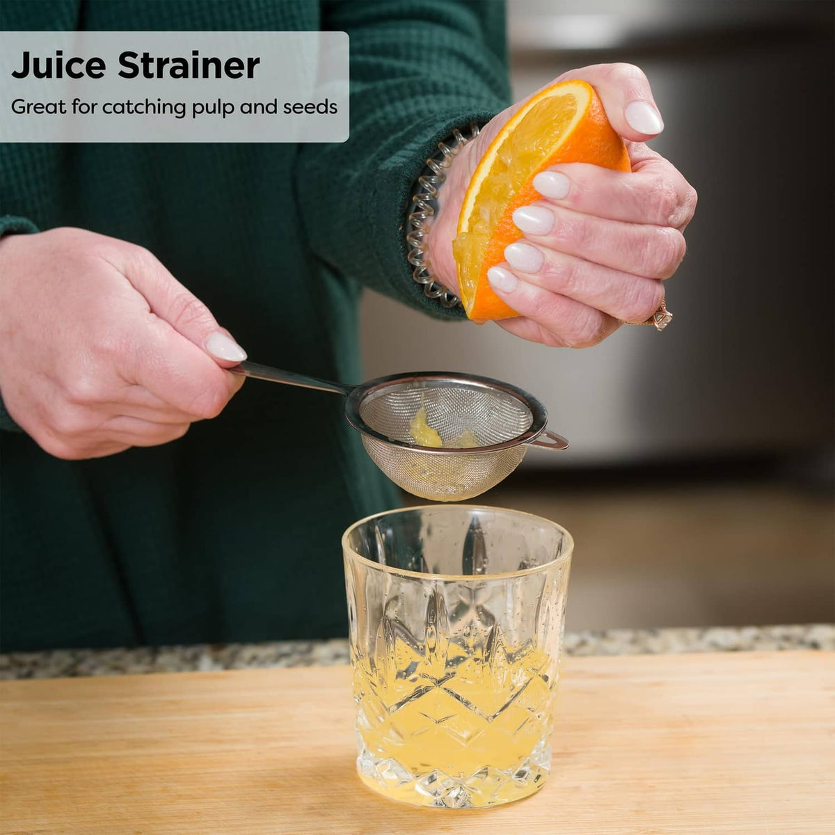 Stainless steel fine-mesh strainer squeezing citrus juice into a glass