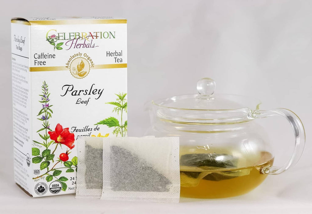 Caffeine-free parsley leaf herbal tea bags box with glass teapot of pale green tea.