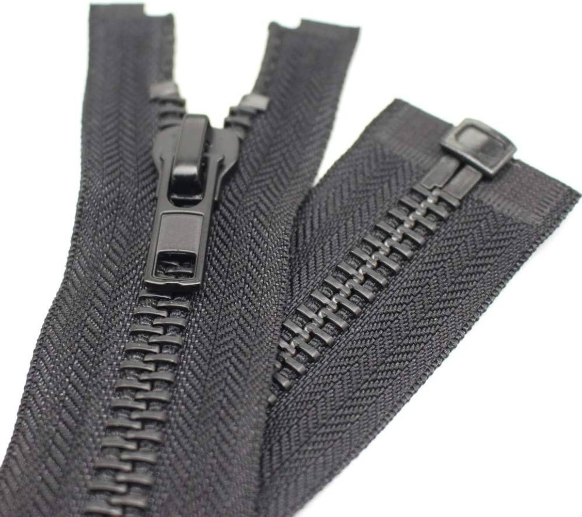 Close-up of separating zipper tape with black metal slider and teeth on dark fabric.