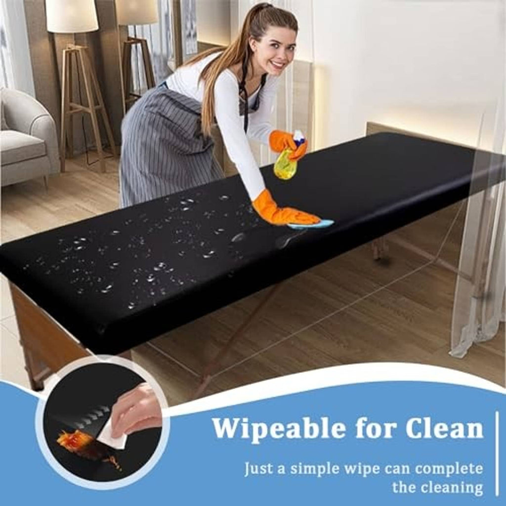 Black wipeable leather massage table cover being cleaned with a cloth
