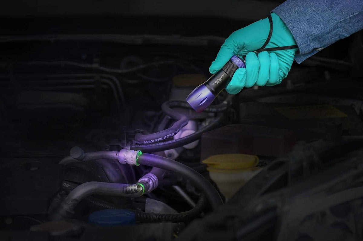 UV dye leak detection on air-conditioning refrigerant lines with purple lamp and glow