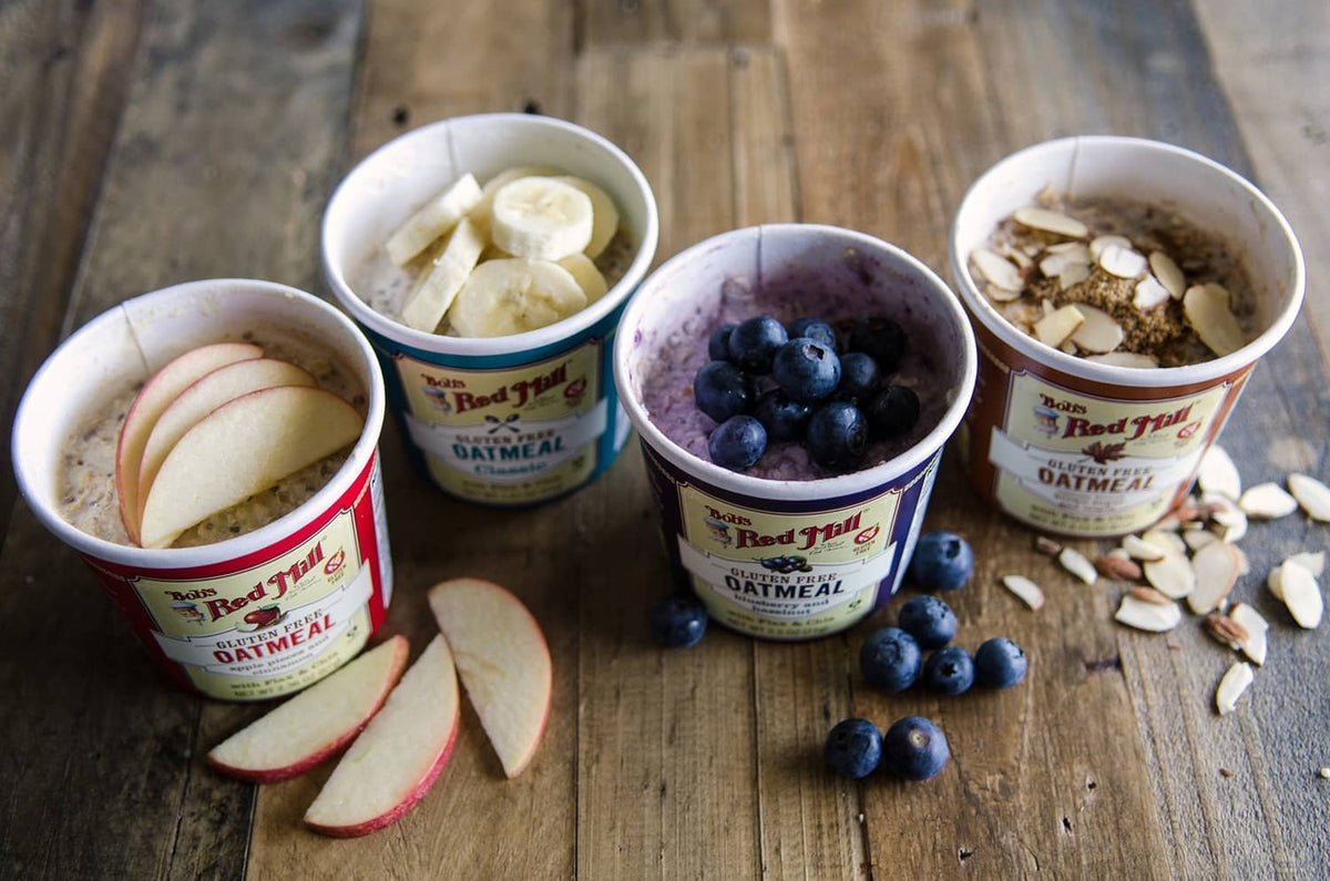Oatmeal cups with banana slices and blueberries, plus oats and granola toppings