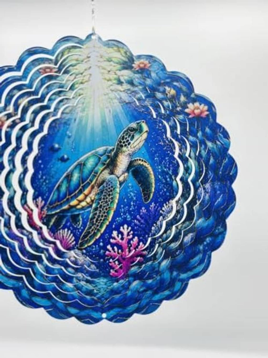 Close-up of blue sea turtle wind spinner with bright center rays and scalloped waves
