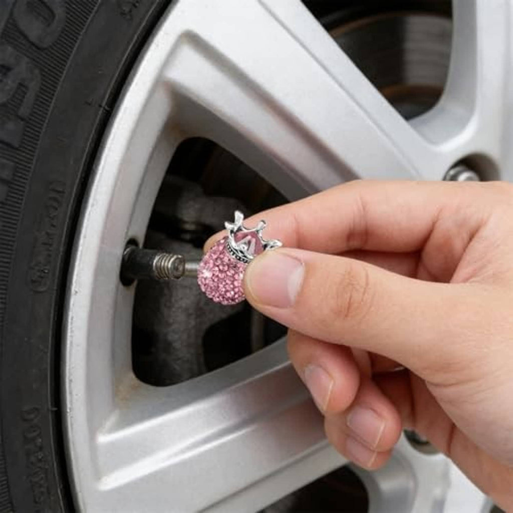 Hand holding a pink rhinestone crown valve stem cap with silver crown detail