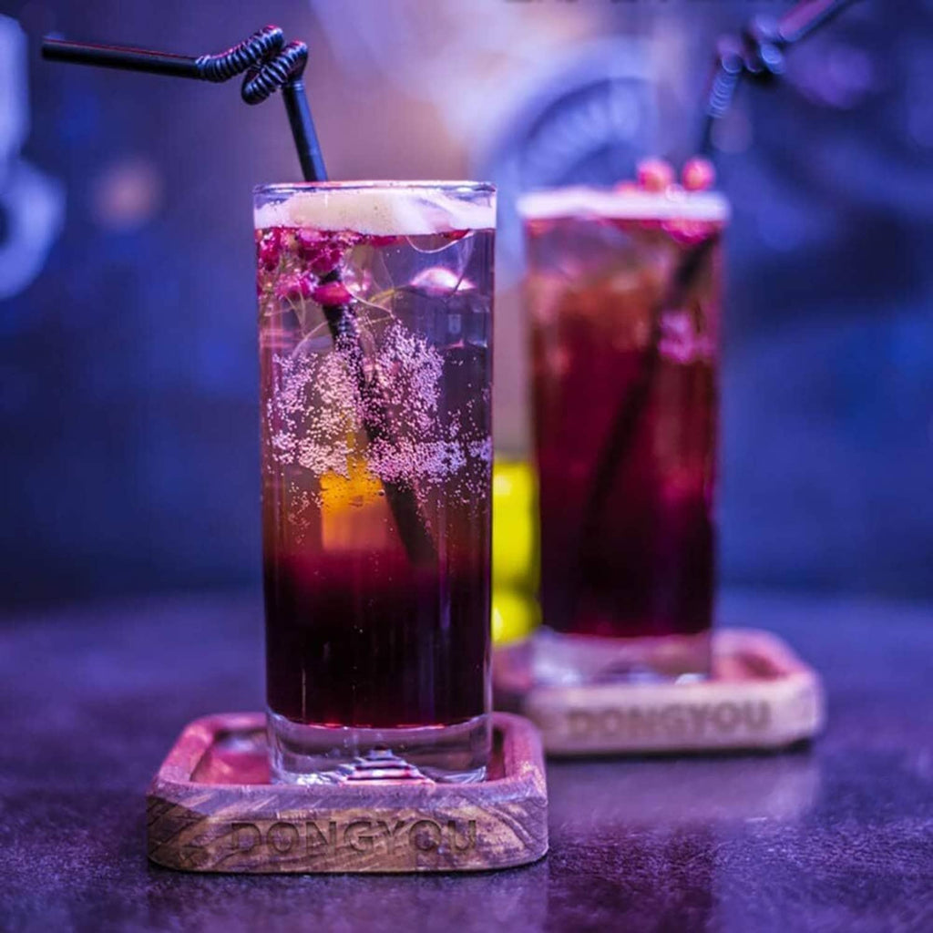 Extra-long drinking straws in colorful cups, showing curly black tips