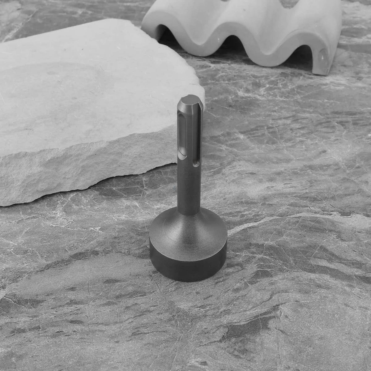 Grey ground rod driver adapter standing on stone, upright long shaft