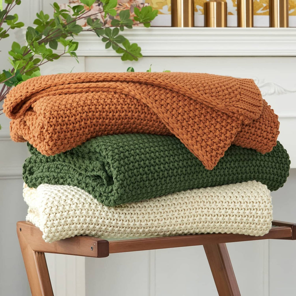 Olive green chunky cable knit throw blanket, folded with cable texture visible