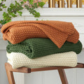 Olive green chunky cable knit throw blanket, folded with cable texture visible