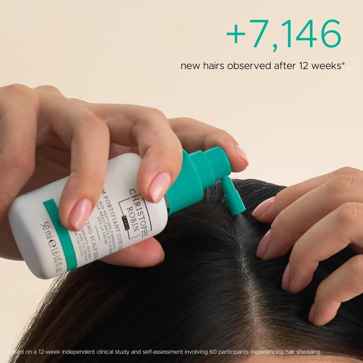 Hands applying scalp serum from a teal nozzle onto dark hair part near scalp