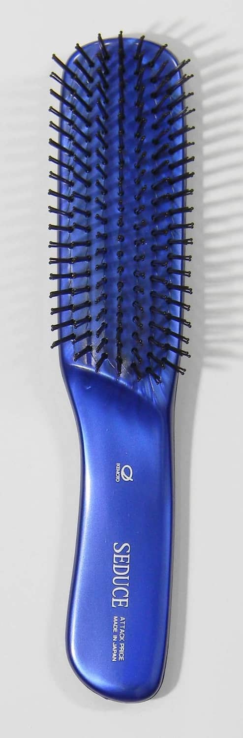 Blue hair care brush (L) with dense bristles on rounded pad, side view