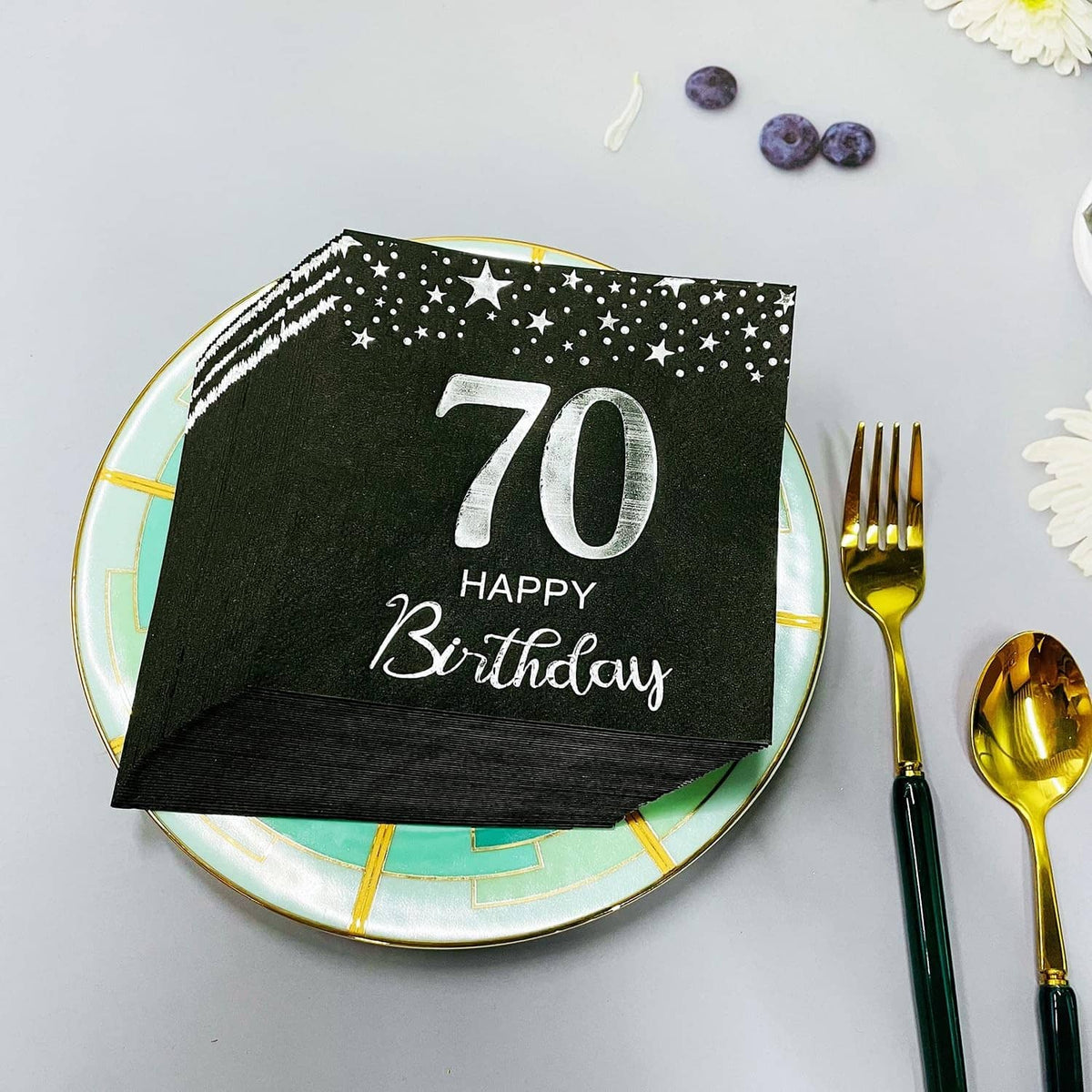 Black star 70th birthday napkins on a plate, silver “70 Happy Birthday” centered