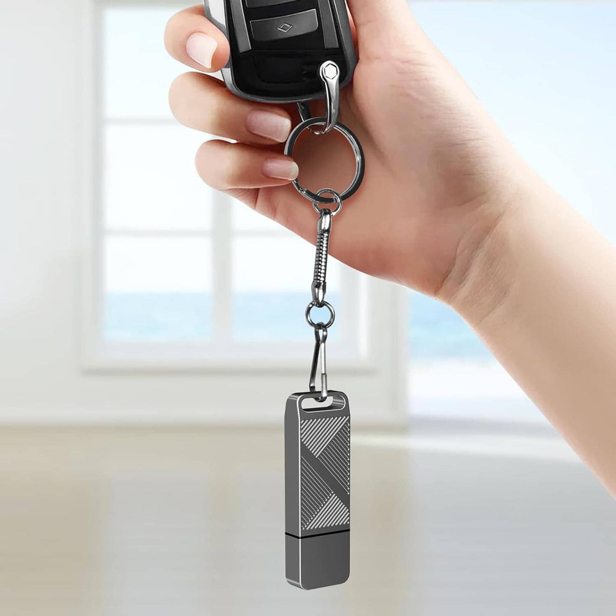 Grey flash drive on keychain with USB-C adapter held by a hand