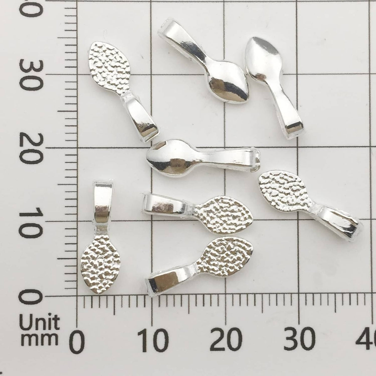 Shiny silver glue-on pendant bails next to a ruler for size reference