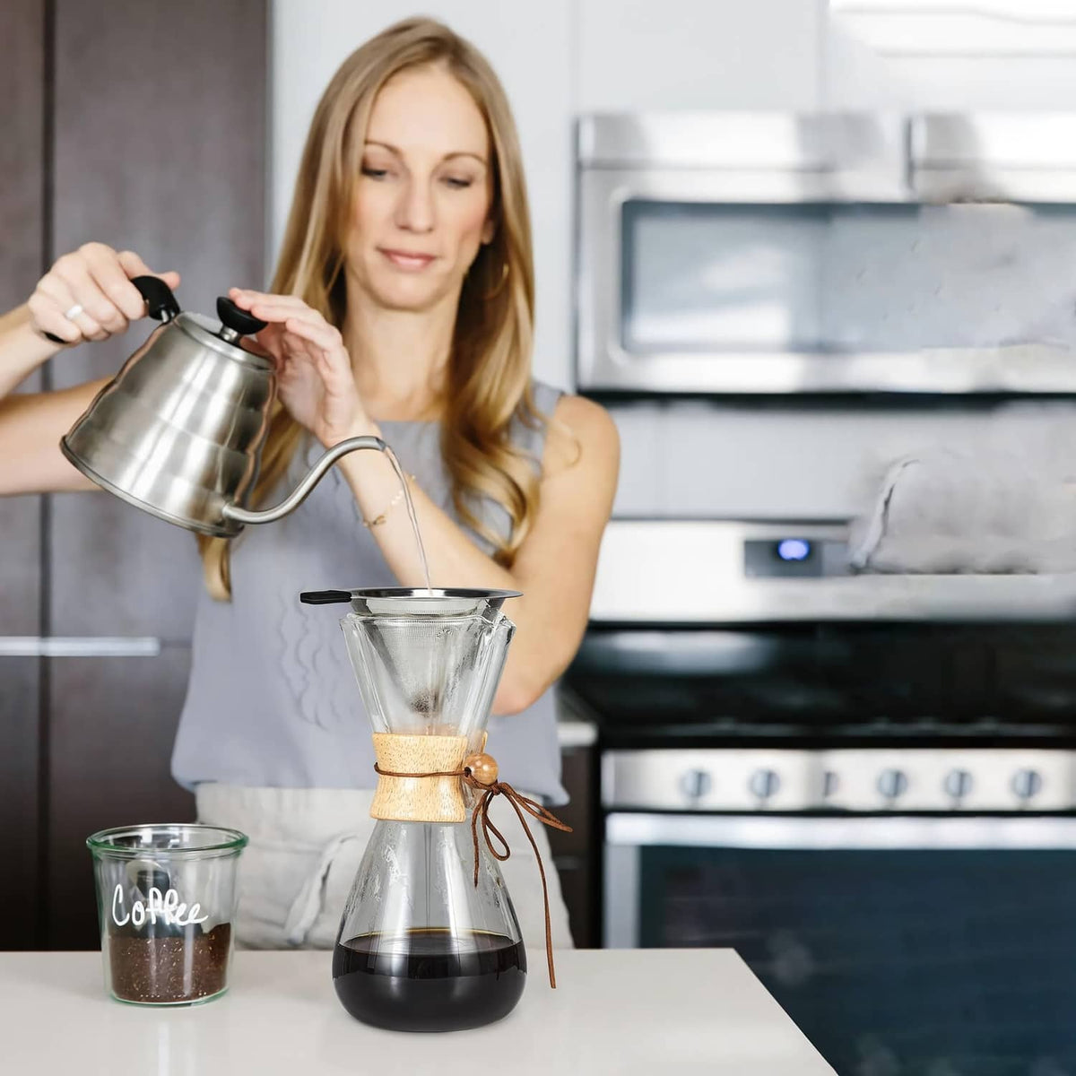 Stainless steel cone coffee dripper with fine mesh filter and black handle over carafe