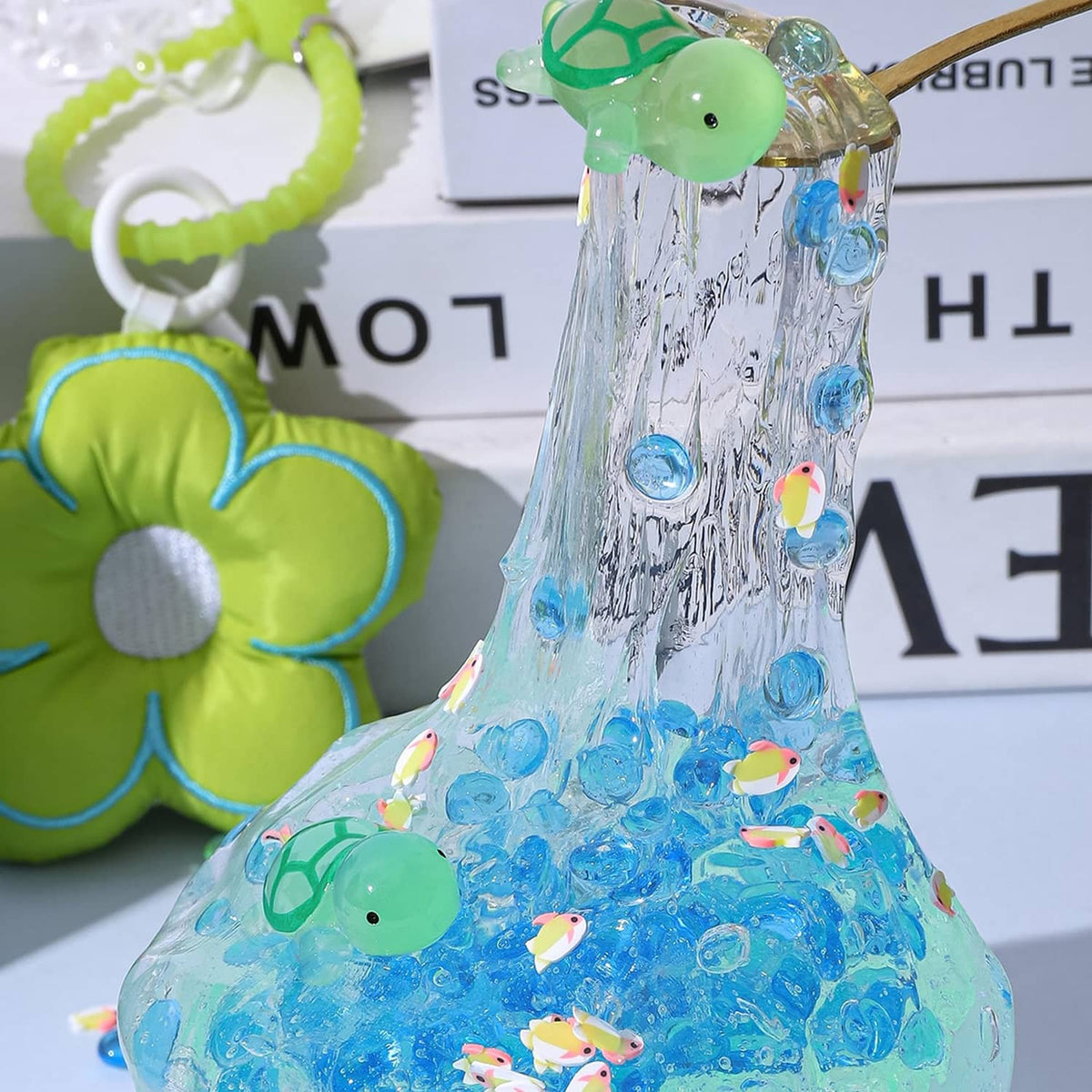 Blue clear glitter slime with green turtle toy and small confetti inside the slime