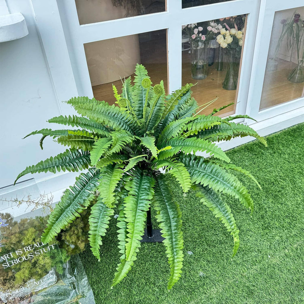 Set of 2 artificial green ferns with arching fronds in a yard setting.