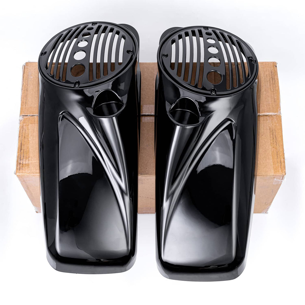 Black speaker lids with circular grille patterns, front view on cardboard backing