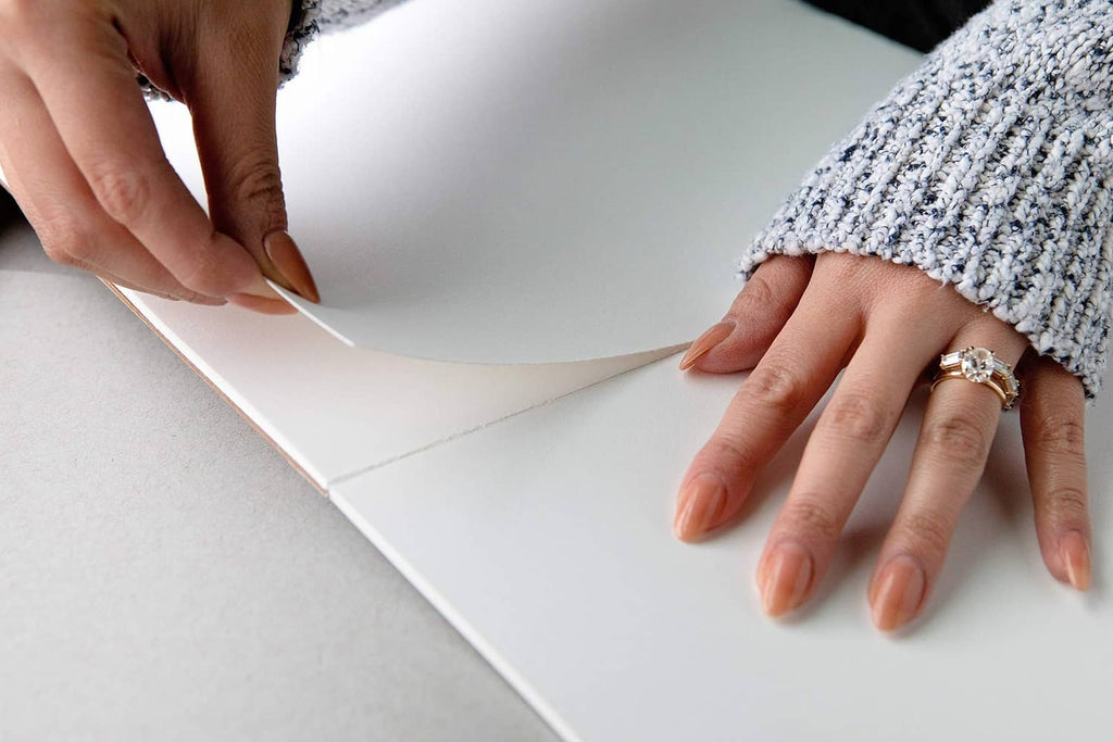 Strathmore Bristol paper pad page being curled by hands for writing and sketching.