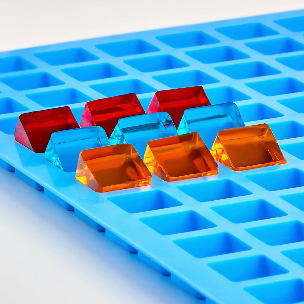 Blue silicone cube candy mold holding colorful translucent cube candies