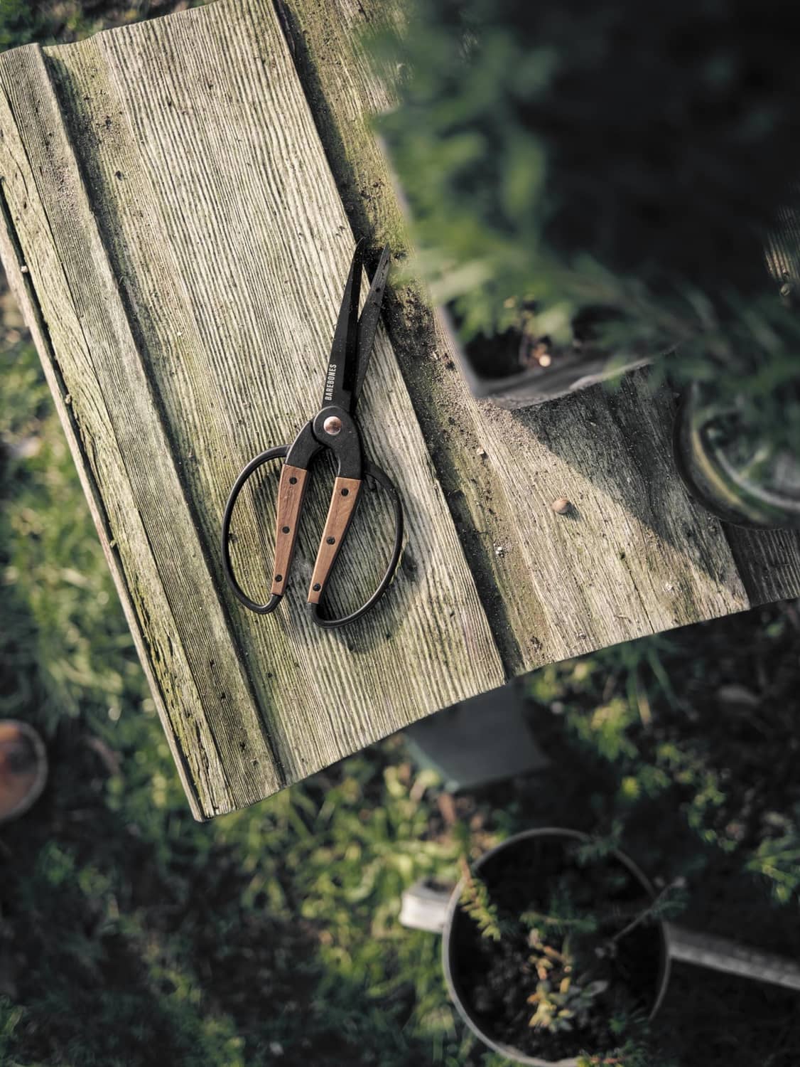 Dual grip garden shears clipped on wooden fence plank, black blades and walnut handle grips