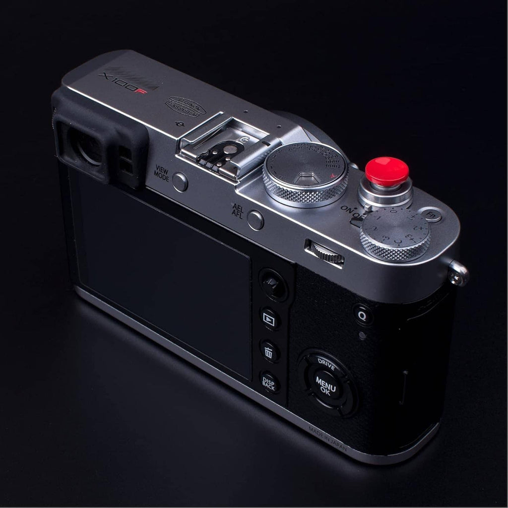 Red shutter release button installed on top of a digital camera body.