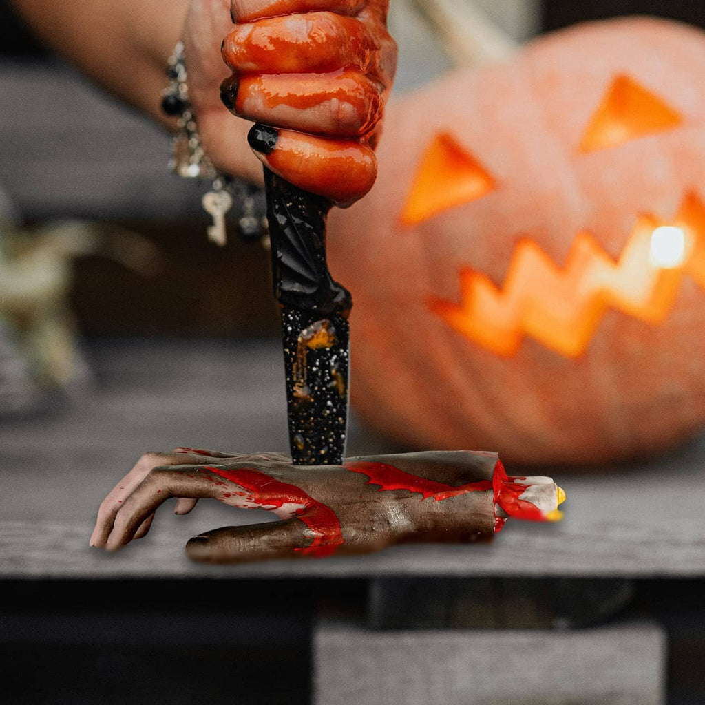 Halloween severed hands and forearm props with smeared blood effects on dark surface