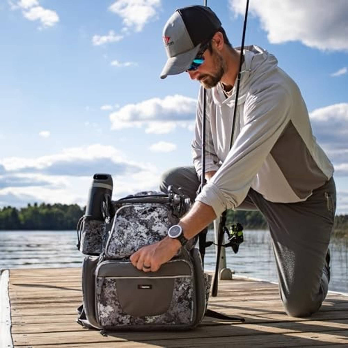 Gray camouflage fishing backpack with tackle boxes and rod holders, worn outdoors