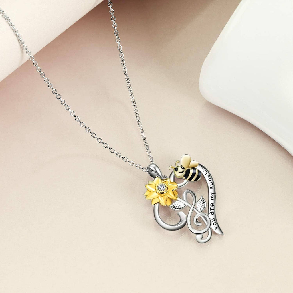 Silver-tone chain necklace with bee, gold flower, and heart-shaped pendant