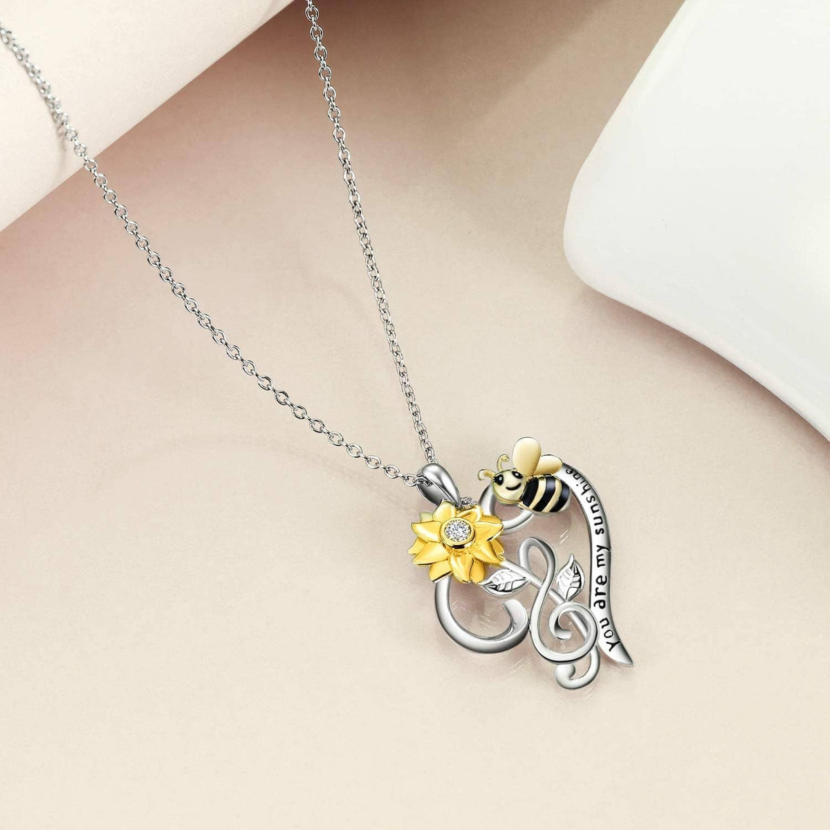 Silver-tone chain necklace with bee, gold flower, and heart-shaped pendant