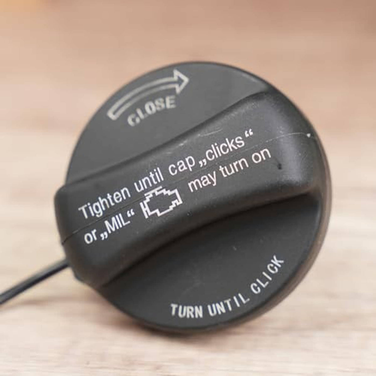 Black fuel tank filler cap close-up with CLOSE arrow and TURN UNTIL CLICK text