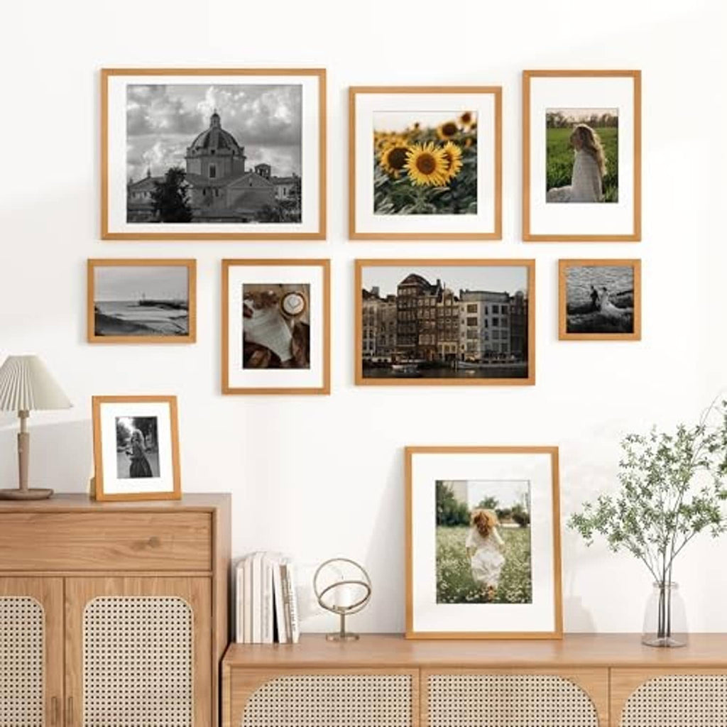 Teak wood picture frames with white mats arranged on a wall in different sizes