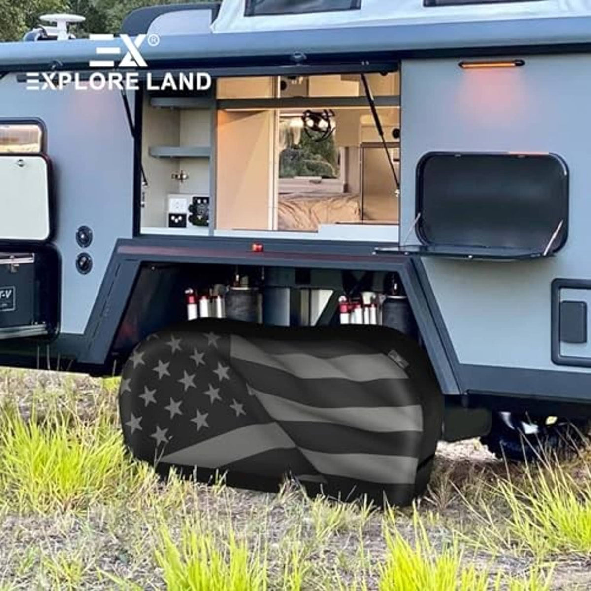Dual-axle tire cover with black American flag star-and-stripe pattern on an RV