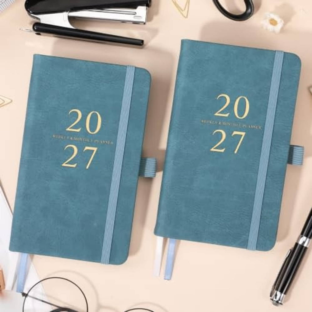 Teal pocket planners with gold “20 27” cover and blue spine, pen loop tab