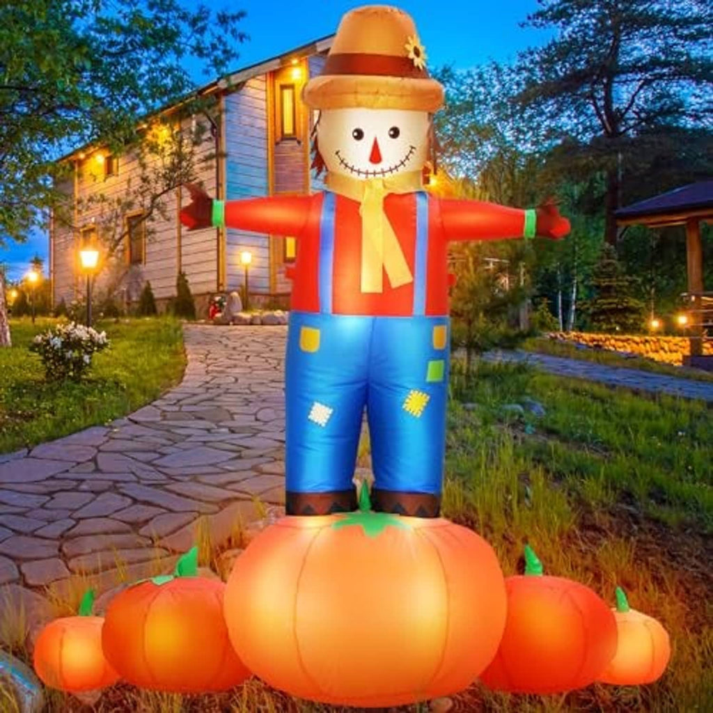 Inflatable scarecrow decoration with blue overalls and orange pumpkin pile base, outdoor yard