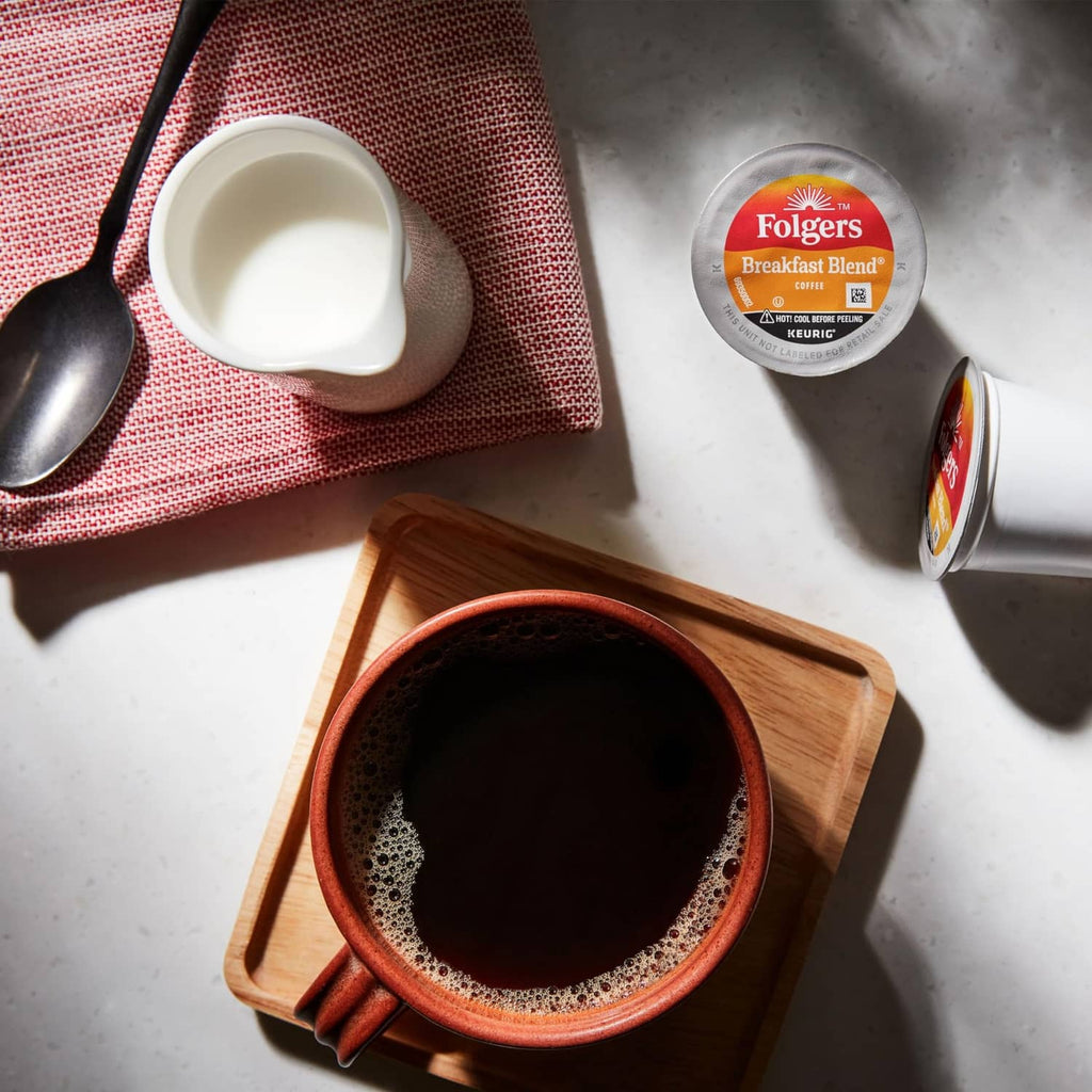 Keurig coffee pod and brewed coffee cups with foam, Folgers Breakfast Blend.