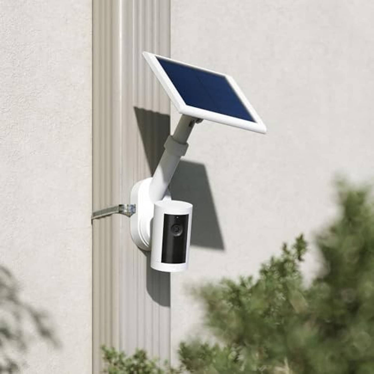 White wall-mounted camera with solar panel on outdoor siding