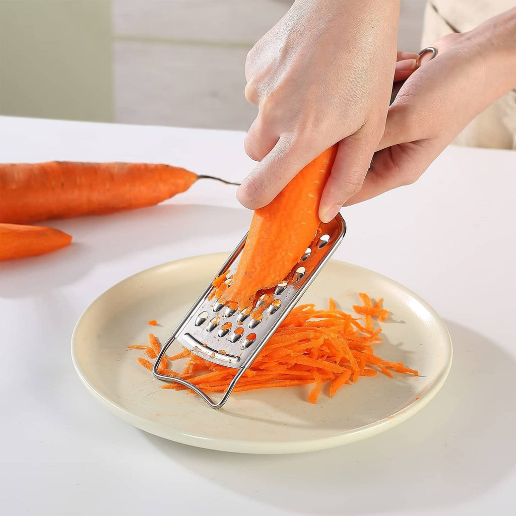 Stainless steel box grater shredding orange carrot on a plate