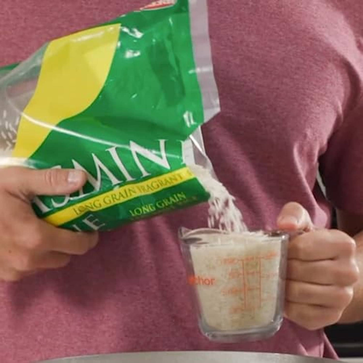 Jasmine long-grain rice bag, held near a clear measuring cup
