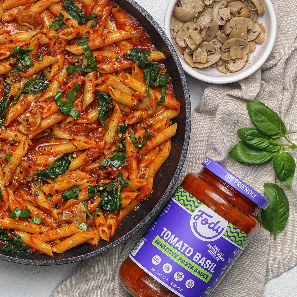 Tomato basil pasta sauce bottle next to penne pasta in red tomato sauce
