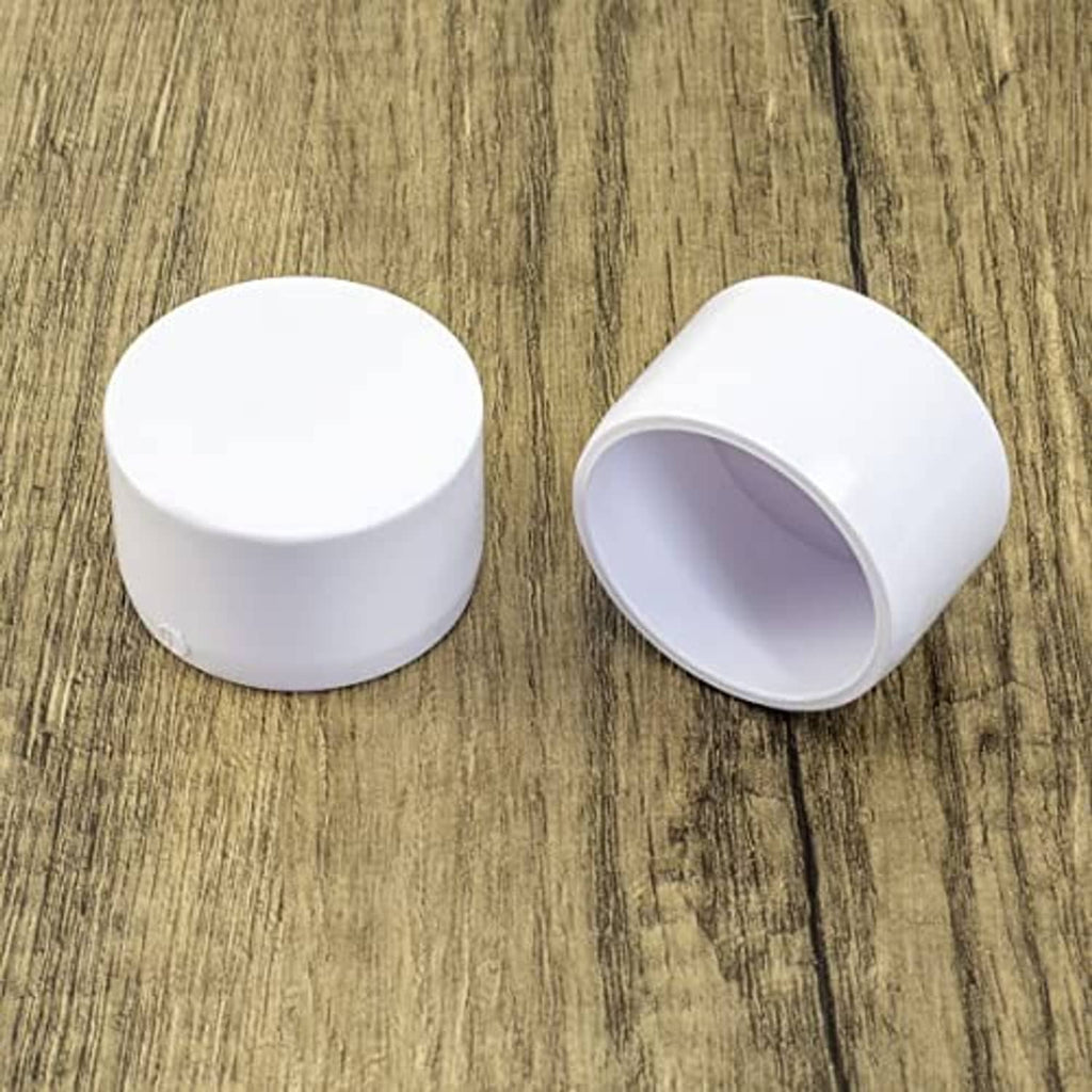 White 1-1/4 in PVC pipe end cap plugs, pair shown in top views on surface