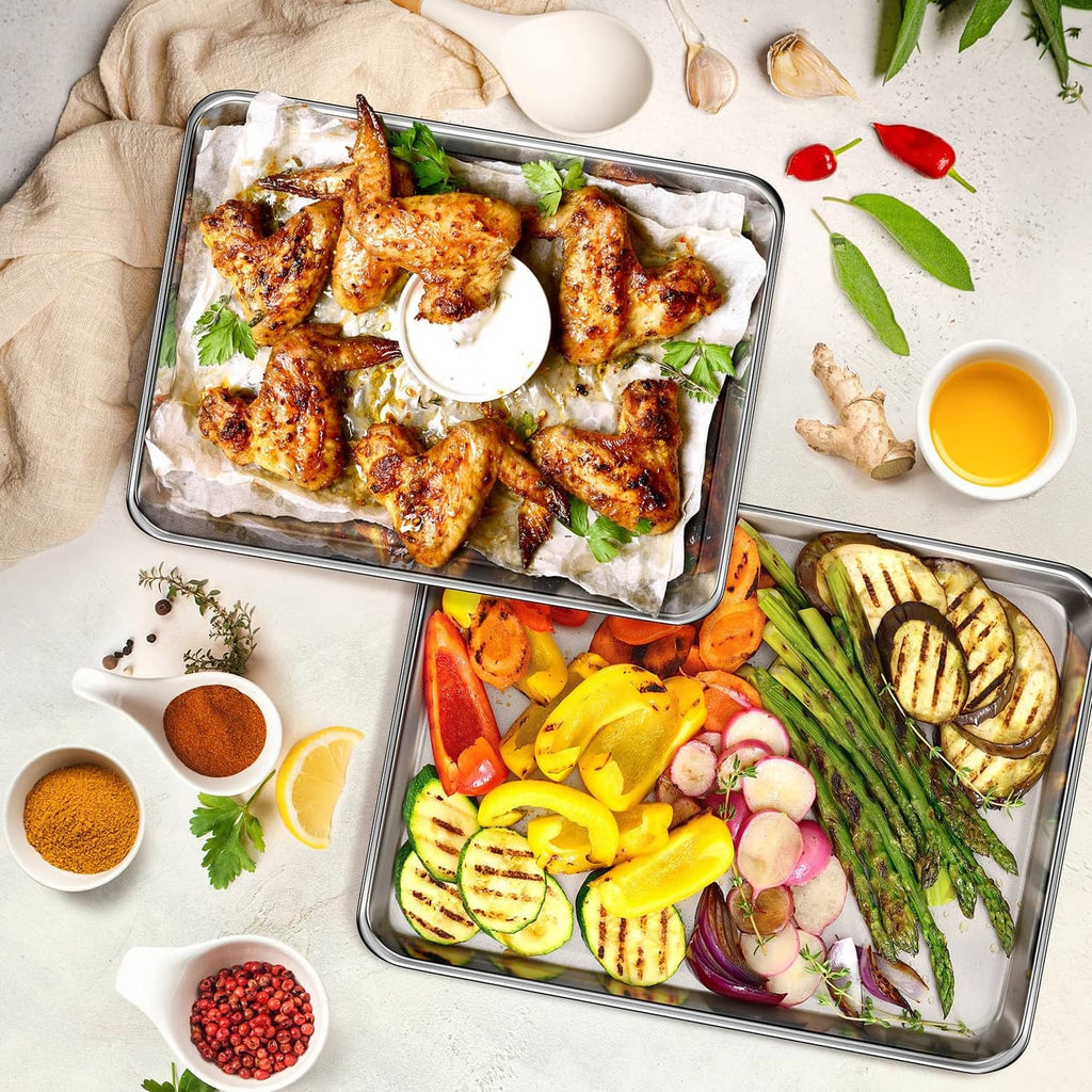 Two silver stainless steel baking sheets with roasted chicken and mixed vegetables