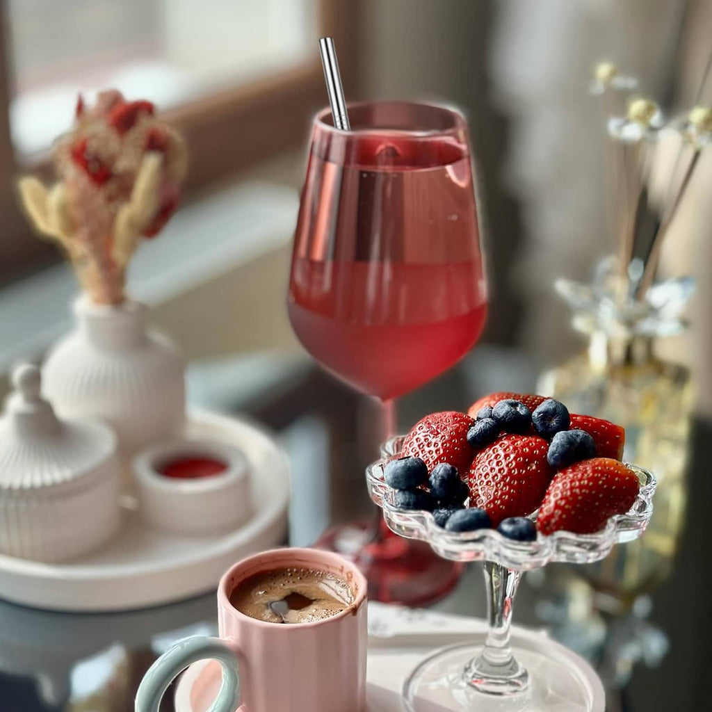 Metal cocktail straw in a red drink glass with dessert on the table