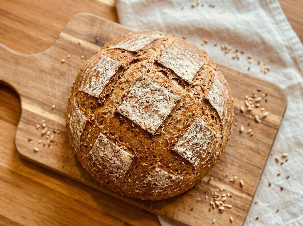 8 grain bread loaf with split top score marks and visible multigrain seeds on a board