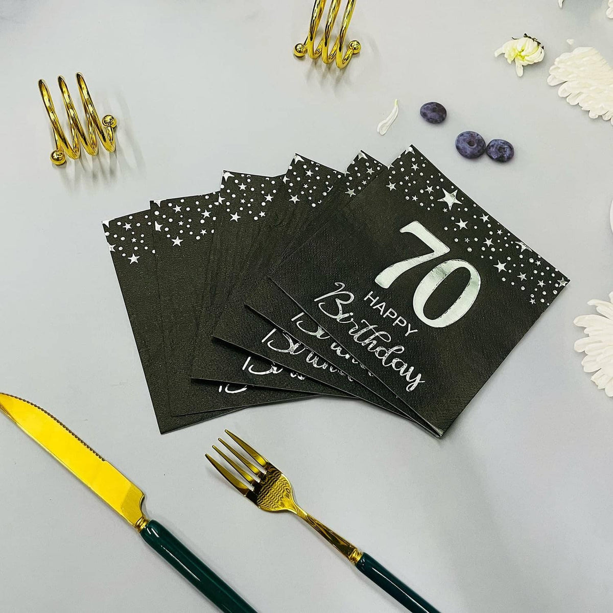Stack of black star 70th birthday napkins with silver “70 Happy Birthday” lettering