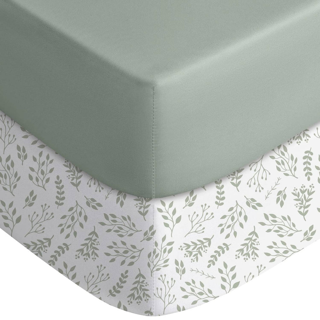 Fitted crib sheet with light green solid top and white leaf-print skirt corners
