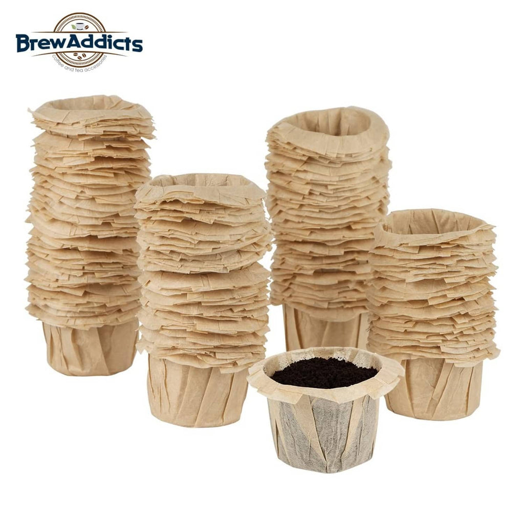 Multiple stacked brown unbleached paper coffee filter cups, one filled with grounds