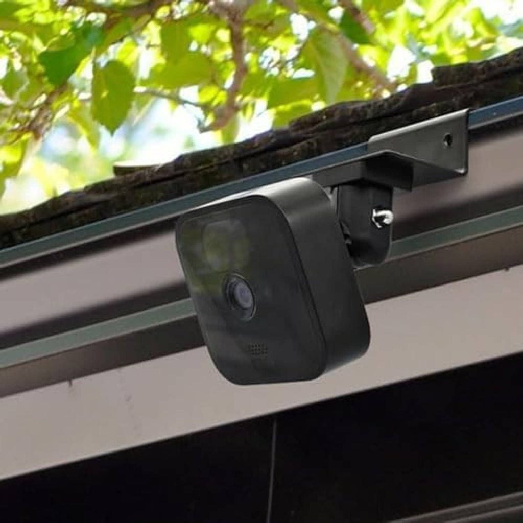 Black rectangular camera or solar mount housing attached to gutter bracket with screws