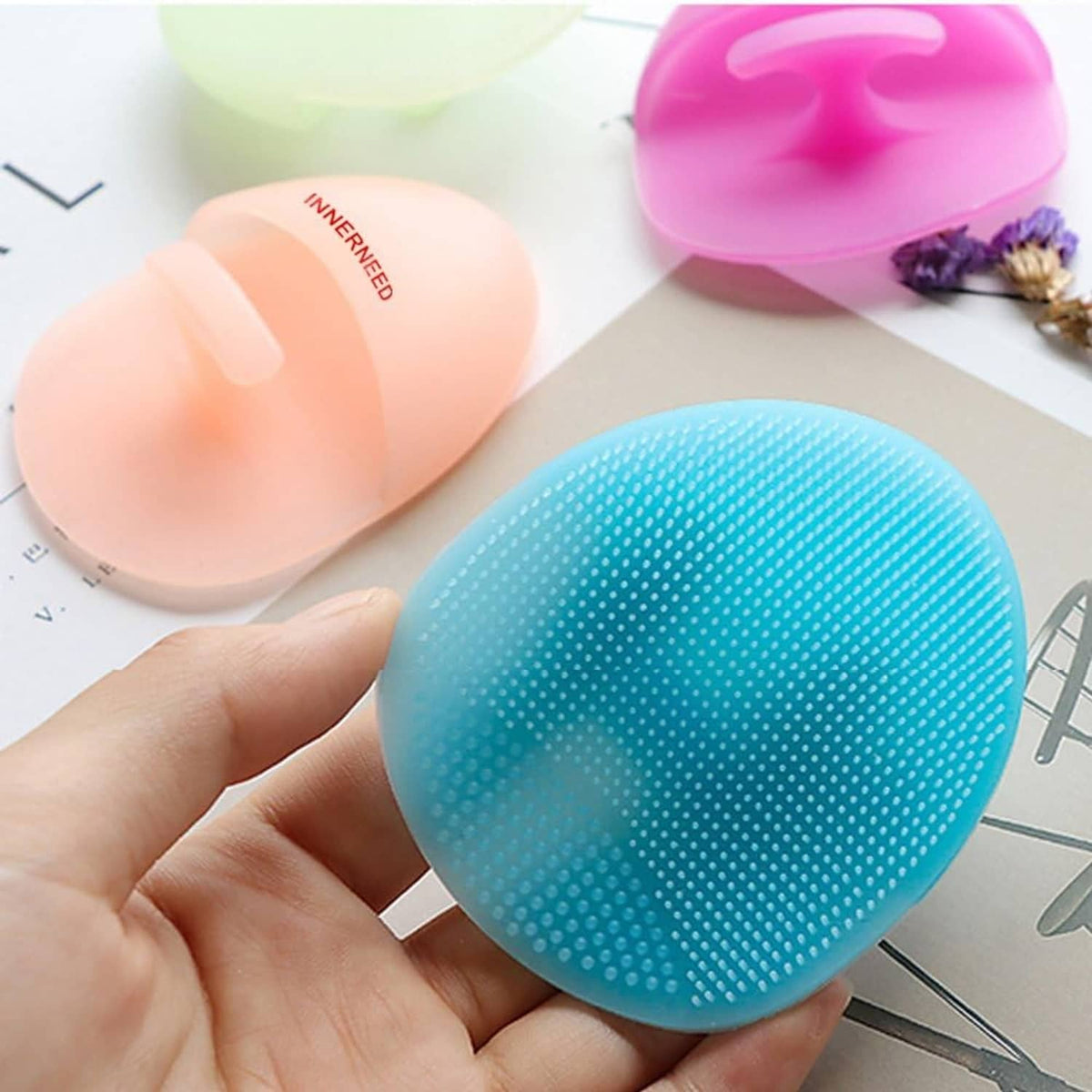 Blue silicone facial cleansing brush with textured dot surface and oval massager shape