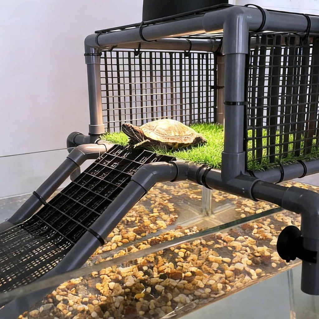 Turtle on black non-slip ramp beside grassy basking dock within gray metal frame
